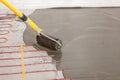 Electric floor heating system installation in new house. Worker align cement with roller. Royalty Free Stock Photo