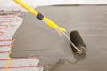 Electric floor heating system installation in new house. Worker align cement with roller. Royalty Free Stock Photo