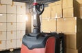 Electric forklift pallet jack with cargo shipment boxes. Stack of cardboard boxes on pallet rack at the warehouse storage. Royalty Free Stock Photo