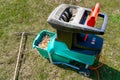 Electric garden shredder with weathered lawn and pile of cut tree branches in the background. Cleanup around the house