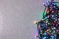 Electric garland of colored light bulbs on a silver background with glitter. Top view, copy space Royalty Free Stock Photo