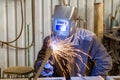 An electric and gas welder in an electromechanical workshop welds a metal structure at a mechanical assembly site