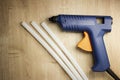 Electric glue gun with silicone sticks on a wooden surface