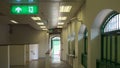 Green emergency exit sign on ceiling in empty corridor tunnel of sky train station Royalty Free Stock Photo