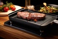 electric grill pan with a sizzling steak on it