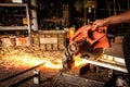 Electric grinder cutting steel. Working man with electric grinder tool in factory with fire sparks.