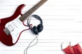 Electric guitar with headphones and red sneakers on white wooden