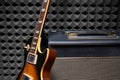 Electric guitar leaning on Guitar Amplifier Combo over acoustic foam background Royalty Free Stock Photo