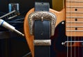 Electric guitar and leather strap with silver buckle. Close-up with glass slide, blues harp and cable jack.