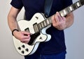 Man playing a white electric guitar with humbucker pickups.