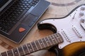 Electric guitar next to a laptop with a pick online guitar lessons