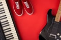 Electric guitar, synthesiser and red stylish sneakers, on red background Royalty Free Stock Photo