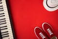 Electric guitar, synthesiser and red stylish sneakers, on red background Royalty Free Stock Photo