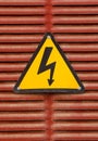 Electric hazard advert sign on a red metal wall background