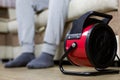 Electric heat gun on the floor warms the feet of a man in socks