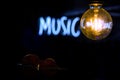 Electric incandescent lamp on the background of half-blurred neon music inscription with a double bass below Royalty Free Stock Photo