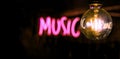 Electric incandescent lamp on the background of half-blurred neon music inscription