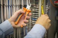 Electric installation work. Screwdriver and pliers in hands of an electrician on background of electric cabinet. Royalty Free Stock Photo