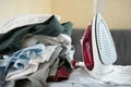 Electric iron and pile of clothes on ironing board Royalty Free Stock Photo