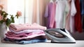 Electric iron and pile of clothes on ironing board Royalty Free Stock Photo