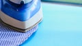 Electric iron and shirt on ironing board in room on a pink background. iron blue striped shirt Royalty Free Stock Photo