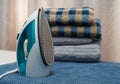 Electric iron stands on a table near clean towels