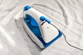 Electric iron and white shirt on ironing board. Ironing clothes close up Royalty Free Stock Photo