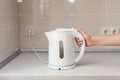 Electric Kettle in hand on the background of the kitchen