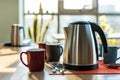 electric kettle in office break room with mugs and spoons nearby Royalty Free Stock Photo