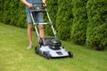 Man mowing grass with electric lawn mower in the backyard