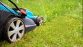 Electric lawn mower machine in garden on grass. Garden and lawn care theme. Banner format with copy space Royalty Free Stock Photo
