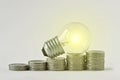 Electric light bulb on raising piles of coins - Concept of increase in electricity bills