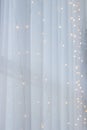 Electric light line on white window curtain. Holiday decoration. Abstract Christmas background. Festive interior design. Royalty Free Stock Photo