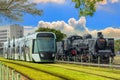 The electric light rail overtaking the steam locomotive symbolizes the evolution of the times and the progress of science.