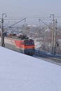 An electric locomotive rides along a snow embankment. Editorial image.