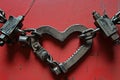 Electric Love: A heart-shaped metal chain connected by jumper cable clamps on a vibrant red background, symbolizing the Royalty Free Stock Photo