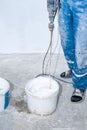 Electric mixer mixes paint in a white bucket