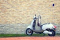 Electric motor scooter parked near a beautiful wall for charging.