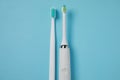 Electric and plastic toothbrushes on turquoise background, flat lay
