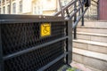 Electric platform lift at building staircase for disabled people with wheelchair sign plate on old city street. Elevator Royalty Free Stock Photo