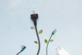 electric plug with green leaves on a blue background, top view okpia place, energy conservation concept