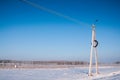 Electric pole of power lines and wires with blue sky on a background of a winter landscape