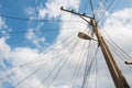 Electric pole with a street lamp and tangled electric cables with blue sky