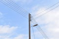 Electric pole with street lamp and wires against blue sky background. Royalty Free Stock Photo