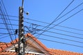 Electric pole and wire cable on blue sky,The roof of the house in the background Royalty Free Stock Photo