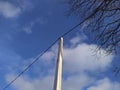 electric pole with wires against the blue sky and white clouds with dry tree branches Royalty Free Stock Photo