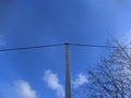 electric pole with wires against the blue sky and white clouds with dry tree branches Royalty Free Stock Photo