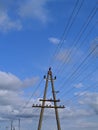 electric pole with wires against the blue sky and white clouds Royalty Free Stock Photo