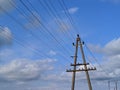 electric pole with wires against the blue sky and white clouds Royalty Free Stock Photo