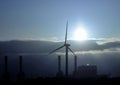 Electric power plant and wind turbine backlit at dawn Royalty Free Stock Photo